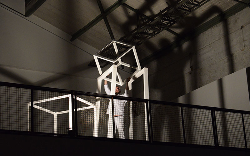 Performer Ronnie Kommene placing a set element on top of another to create a tower